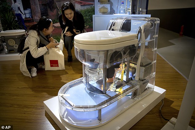 Visitors look at a model of a self-contained toilet at the Reinvented Toilet Expo in Beijing